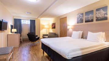 Une chambre d’hôtel avec un grand lit, un bureau avec un ordinateur, une chaise et une télévision.