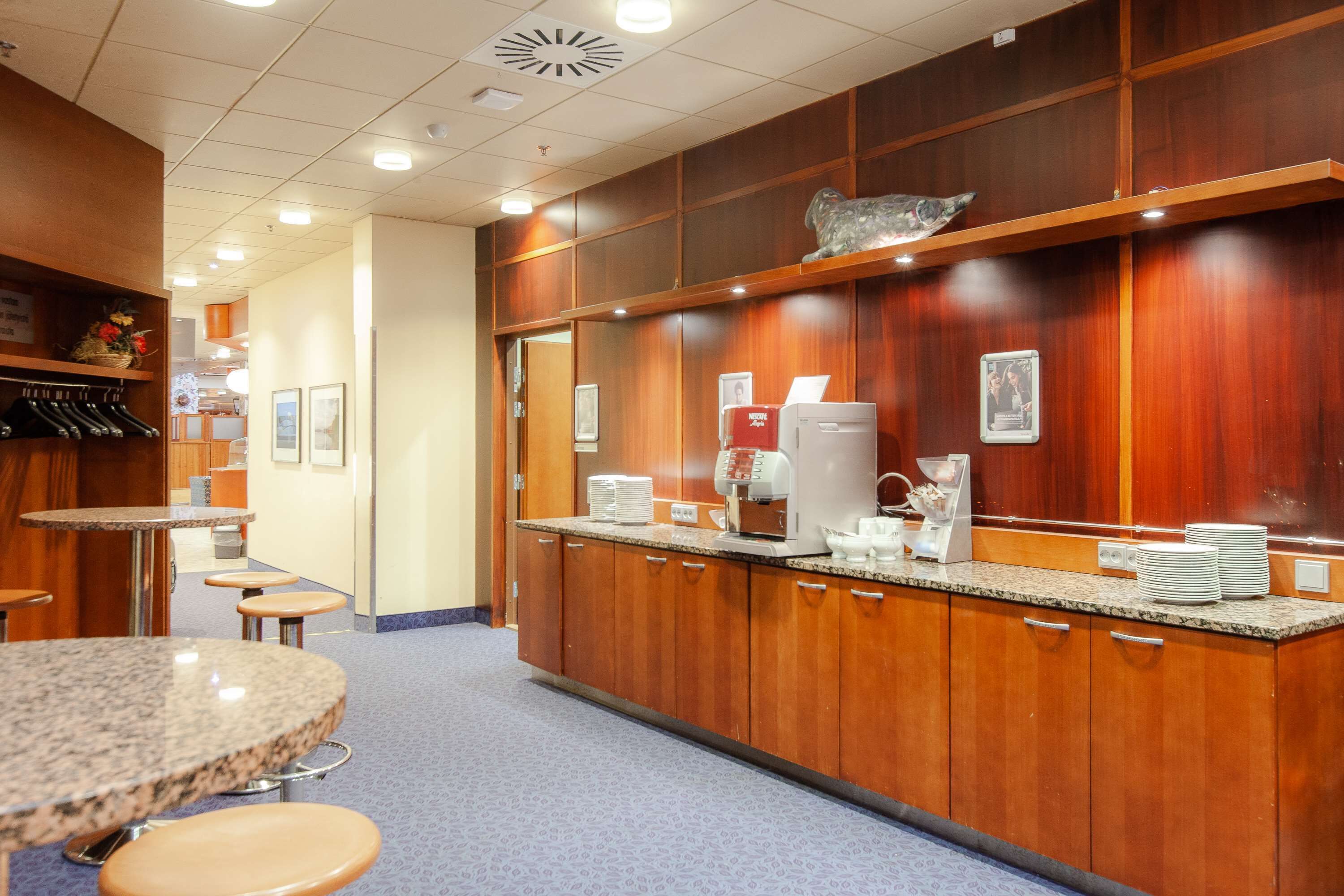 A hotel lobby with wooden paneling, a coffee station, and seating areas.