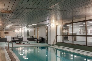 Una piscina interior con sillones de descanso y una zona de recepción.