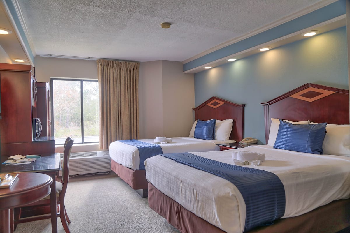 Habitación de hotel con dos camas, un escritorio y una silla.