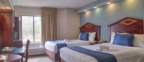 A hotel room with two beds, a desk, and a chair.