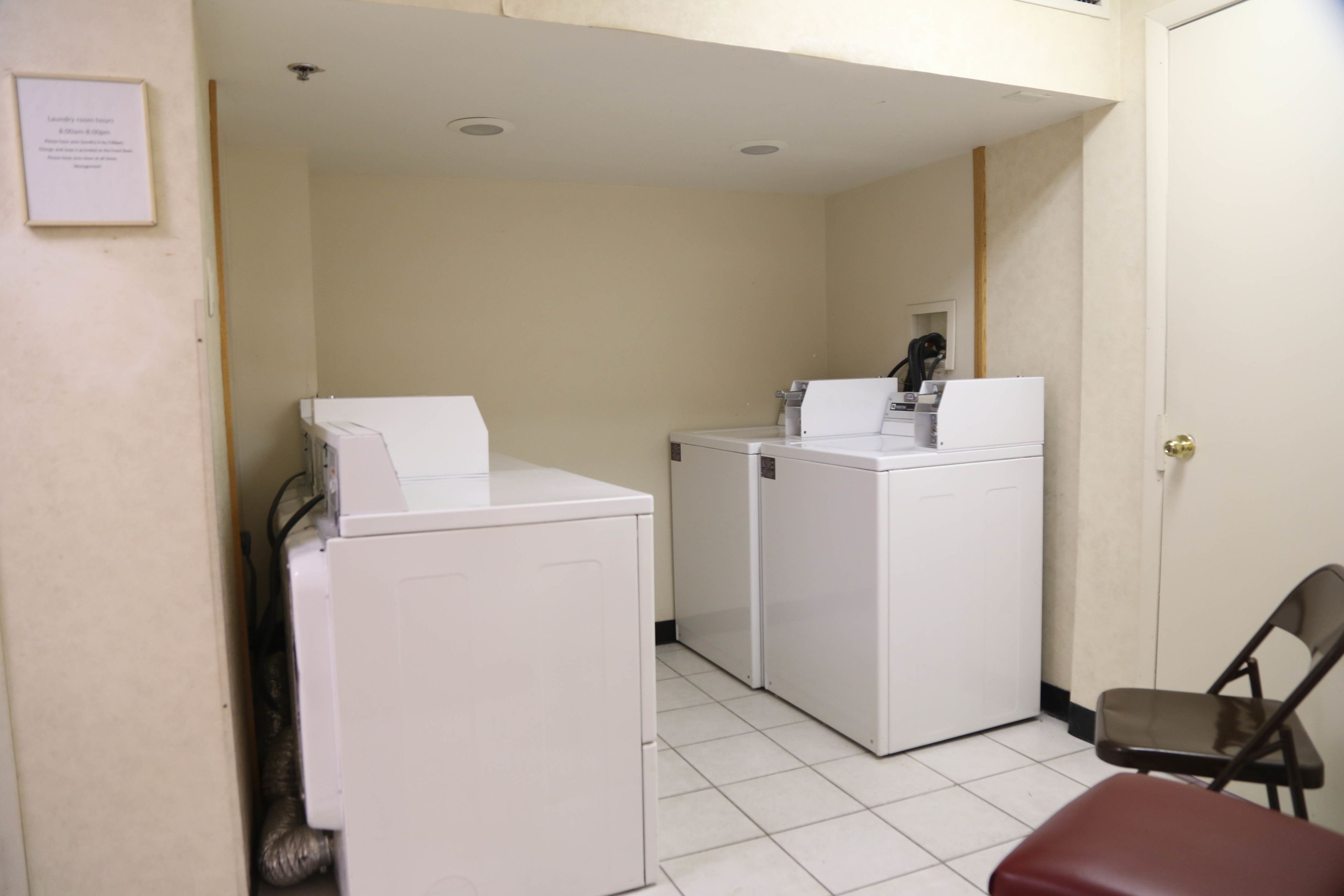 A laundry area with two white washing machines and a chair.