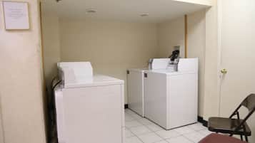 A laundry area with two white washing machines and a chair.