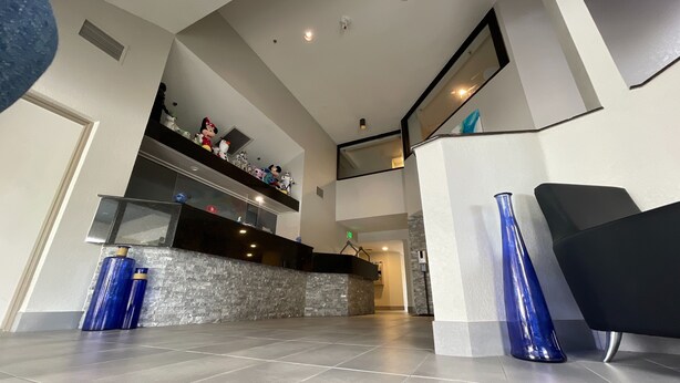 A modern interior with a kitchen area, a staircase, and a seating area with a black sofa. - Destiny Palms Hotel Maingate West (Kissimmee)