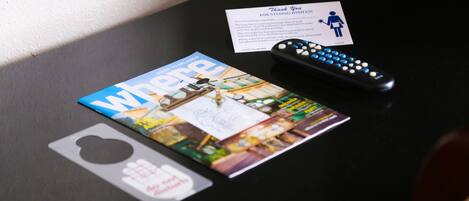 A magazine, a remote control, and a thank you card on a table.