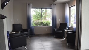A room with two black leather chairs, a large window with curtains, and a tiled floor. - Destiny Palms Hotel Maingate West (Kissimmee)