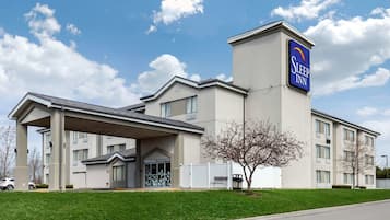 Welcome to Sleep Inn, featuring a modern entrance with a covered walkway and a well-manicured lawn.