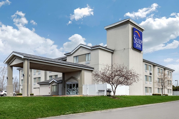 A Sleep Inn hotel with a covered entrance, multiple windows, and a clear sky.