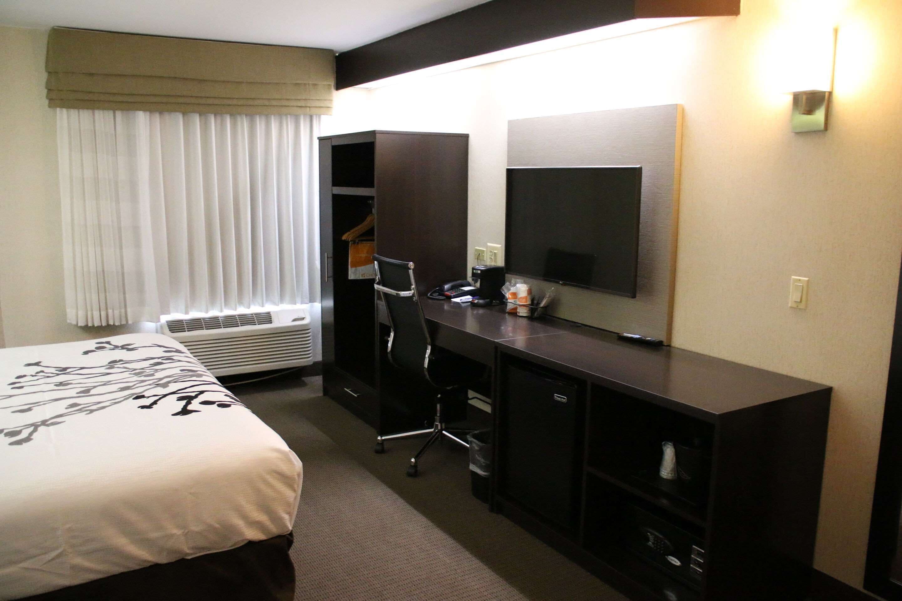 Ein Hotelzimmer mit Bett, Schreibtisch, Sessel, Fernseher und Kleiderschrank.