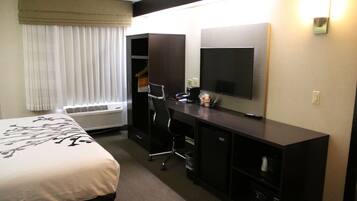 Ein Hotelzimmer mit Bett, Schreibtisch, Sessel, Fernseher und Kleiderschrank.