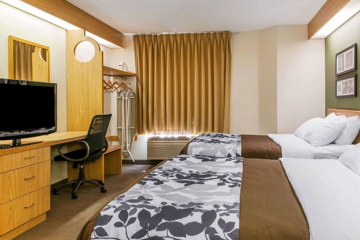 A hotel room with a desk, two beds, a TV, and a wardrobe.