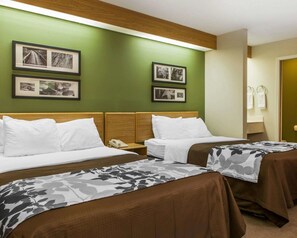 A hotel room with two beds, green walls, and framed pictures on the wall.