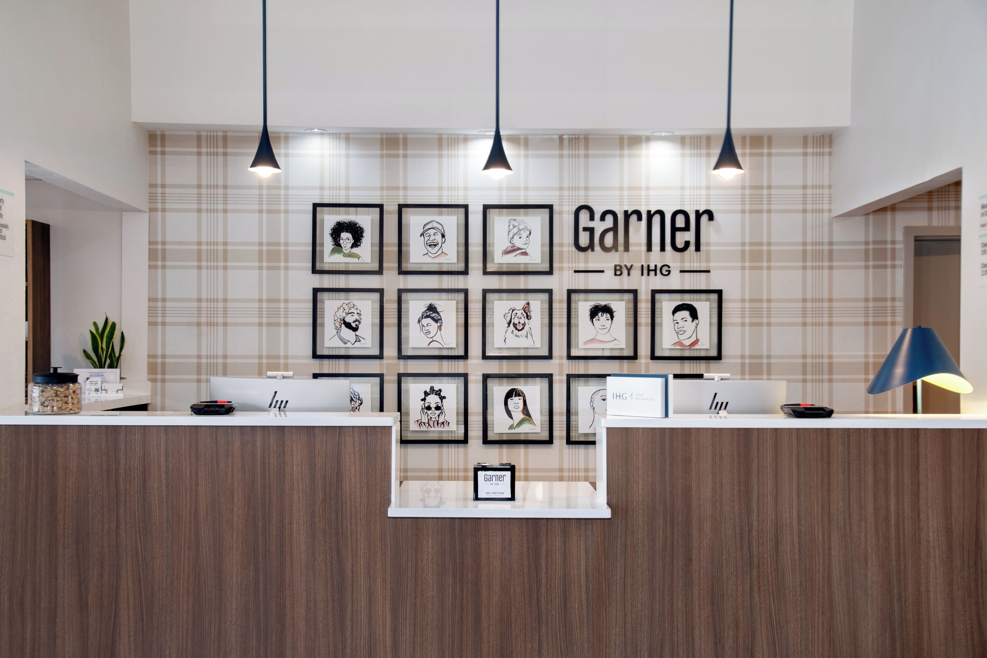 A reception desk with framed artwork on the wall and a sign that reads 'Garner by IHG'.