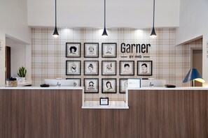 Vastaanottotiski, jonka yläpuolella seinällä on kehystettyjä taideteoksia ja kyltti, jossa lukee: ”Garner by IHG”.