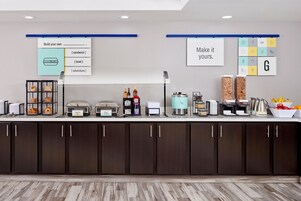 A buffet setup with labeled food stations including eggs, bacon, and whole milk.