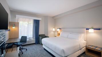 Habitación de hotel con cama, escritorio, silla y televisor.