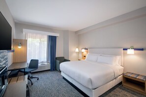 Ein Hotelzimmer mit Bett, Schreibtisch, Stuhl und Fernseher.