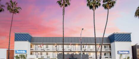 A Travelodge hotel with a two-story structure, a parking lot, and palm trees.