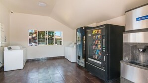 Ein Waschraum mit Verkaufsautomat, Waschmaschine und Kühlschrank.