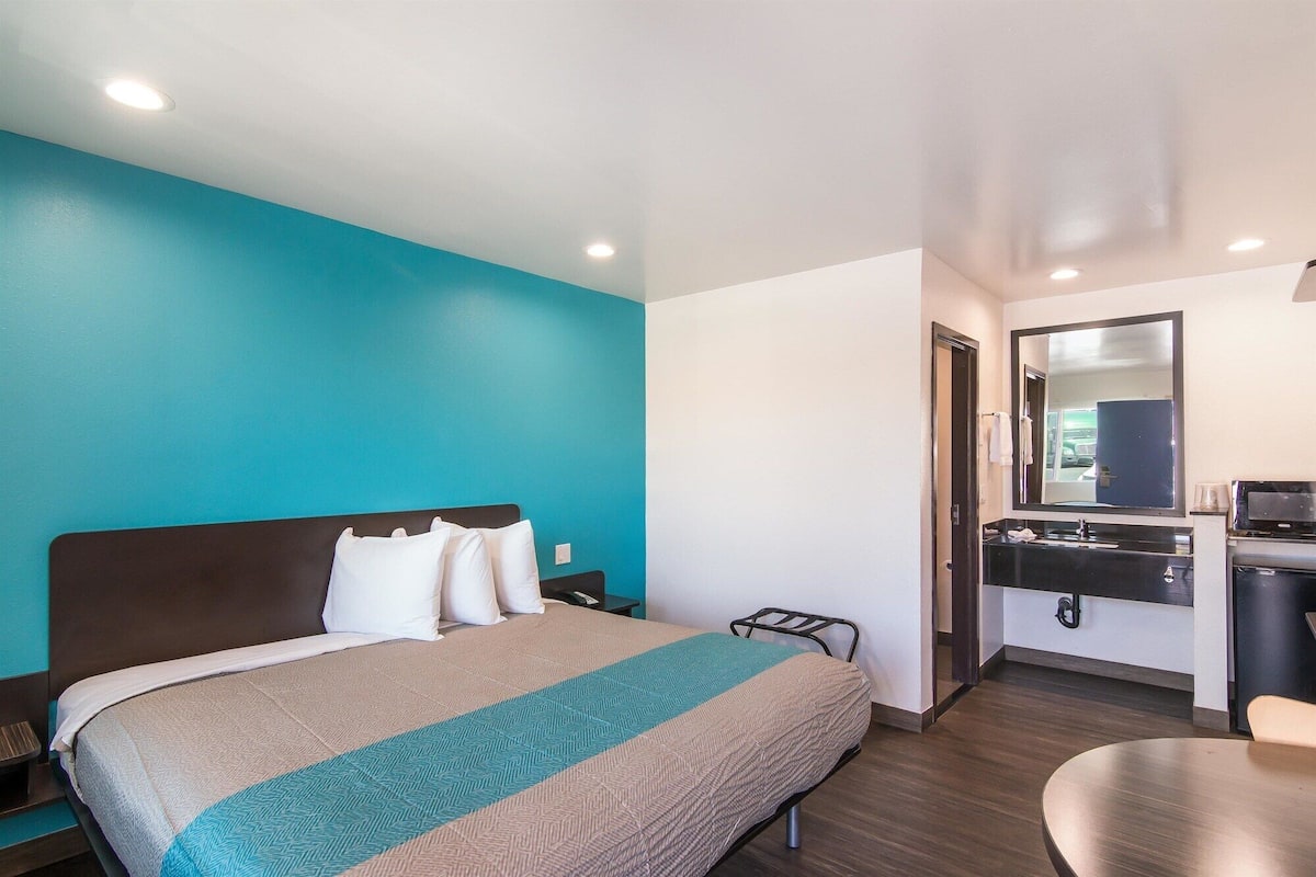 Une chambre d’hôtel équipée d’un lit, d’un bureau, d’une chaise, d’un miroir et d’une salle de bain avec un lavabo et des toilettes.