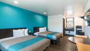 Ein Hotelzimmer mit zwei Betten, einem Badezimmer und einer kleinen Essecke.