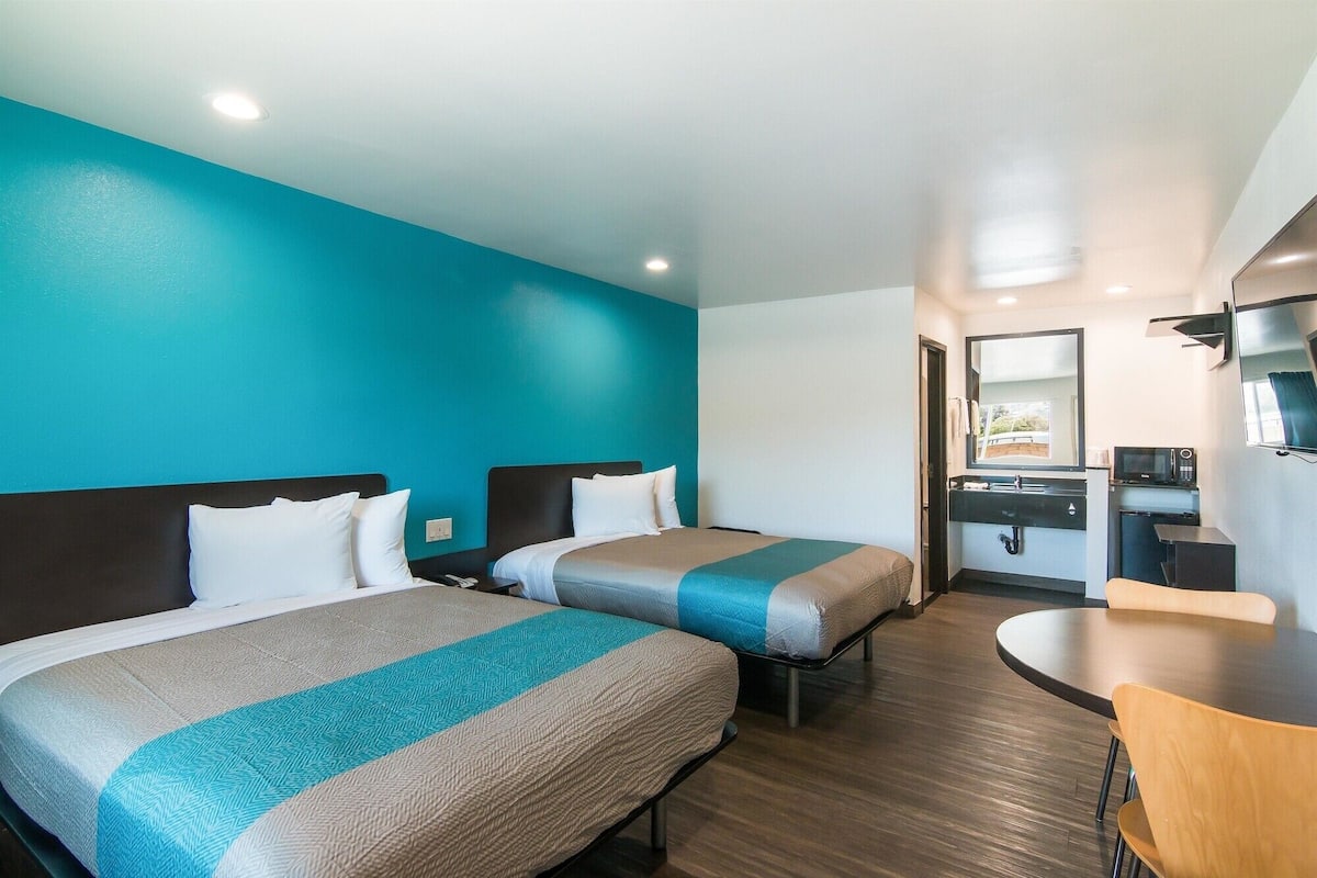 Une chambre d’hôtel avec deux lits, une salle de bain et un petit coin repas.