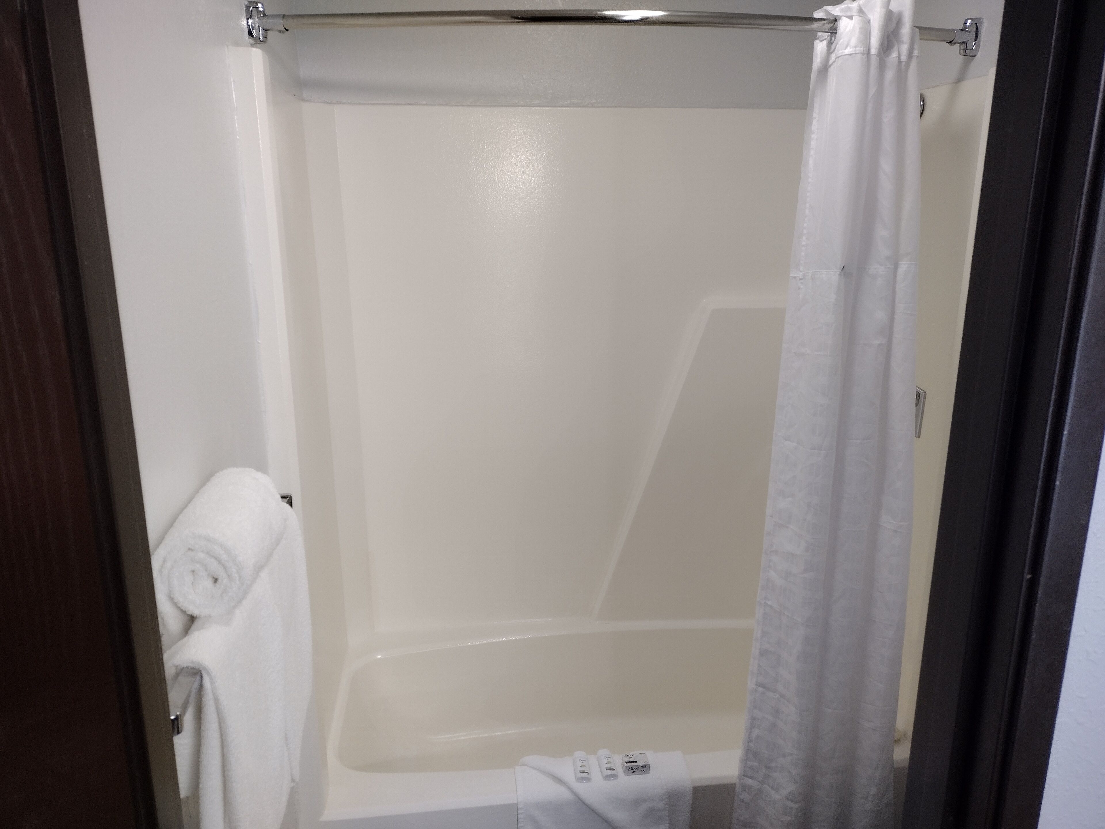 Un baño con bañera, una toalla y cortina de ducha.