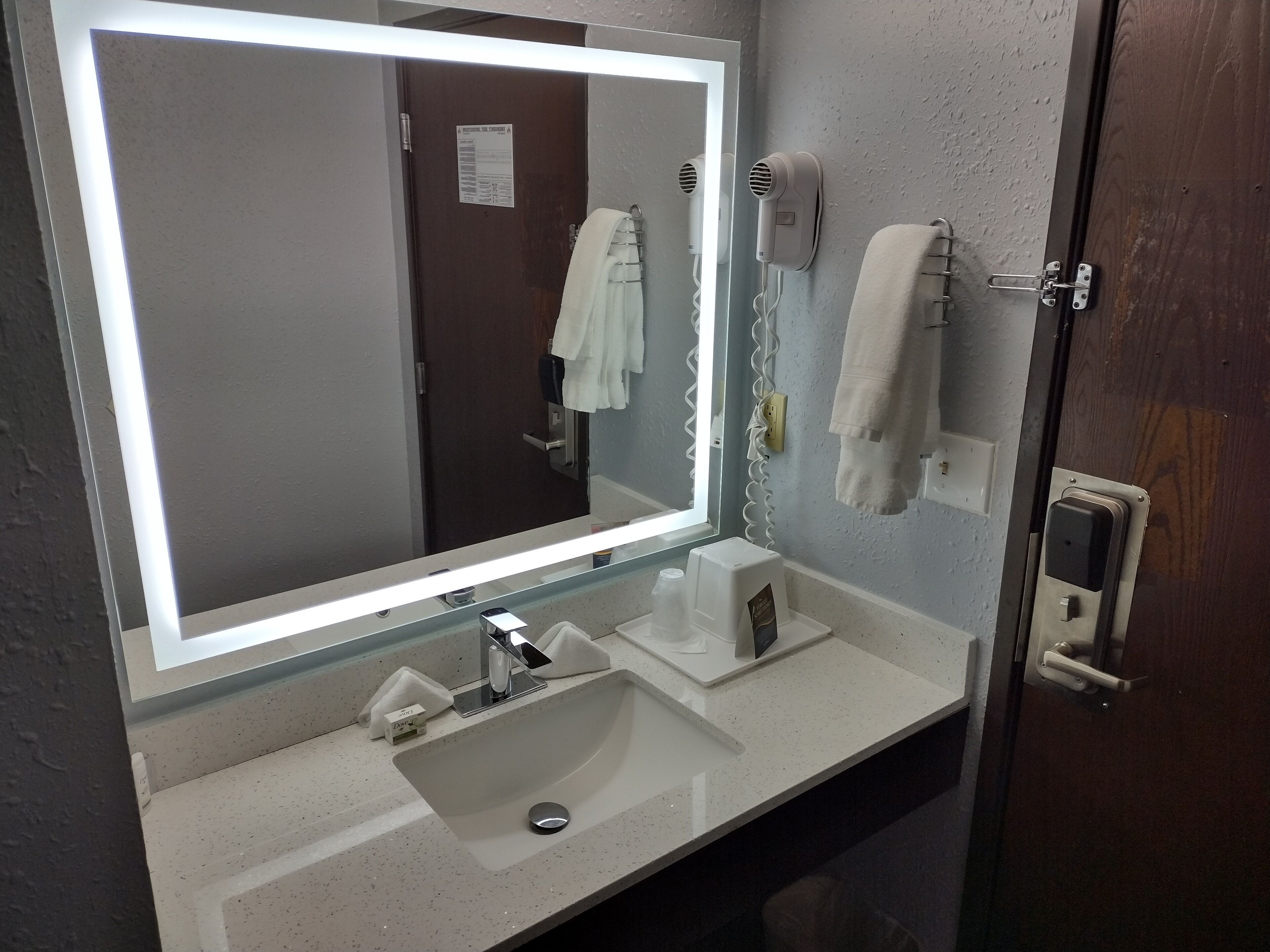 A bathroom with a large mirror, a sink, a towel rack, and a hairdryer.