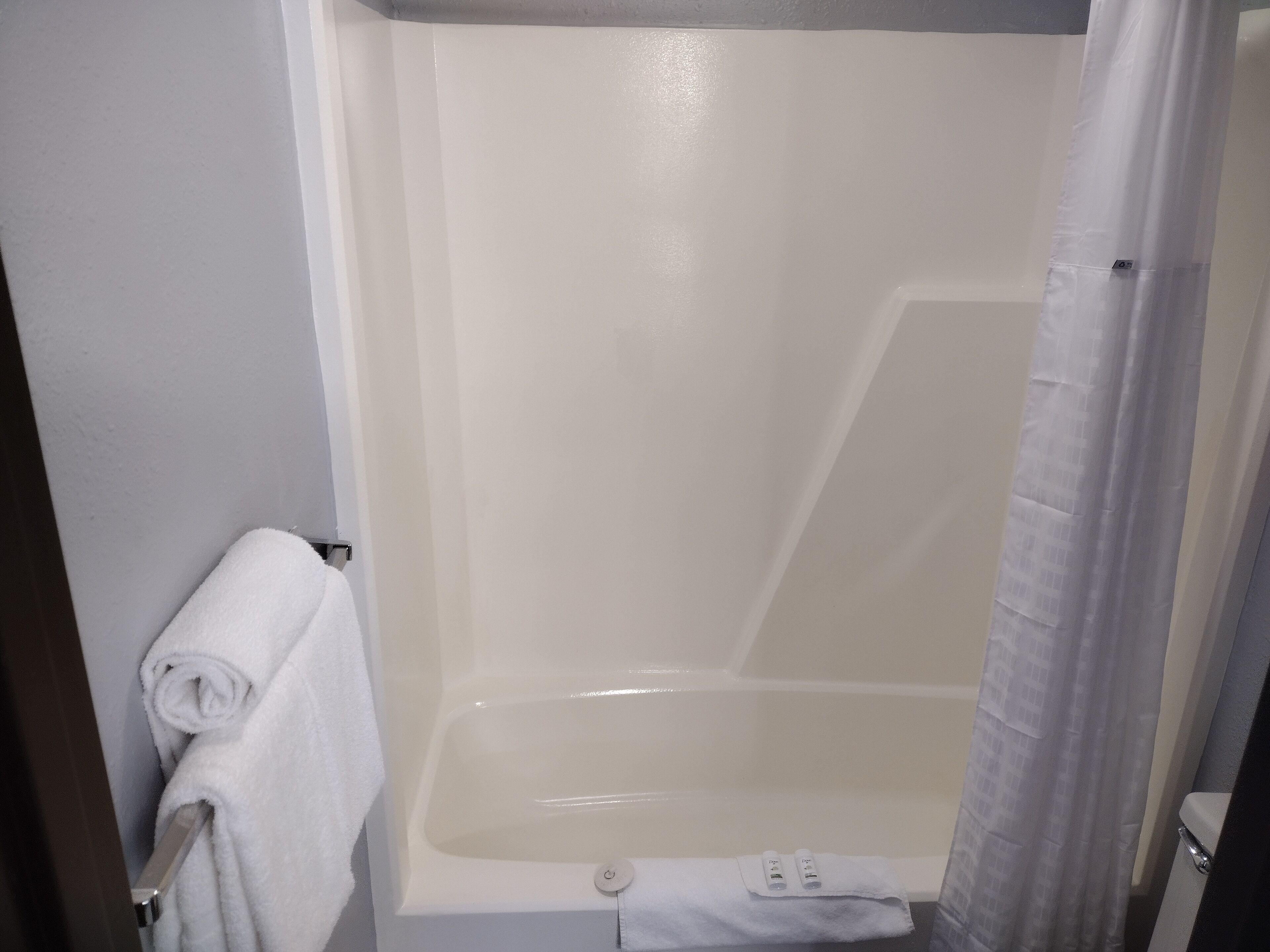 A bathroom with a bathtub, a towel rack, and a shower curtain.