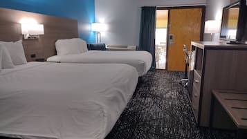 Habitación de hotel con dos camas, un escritorio, una silla, un televisor y una puerta que da a un balcón.