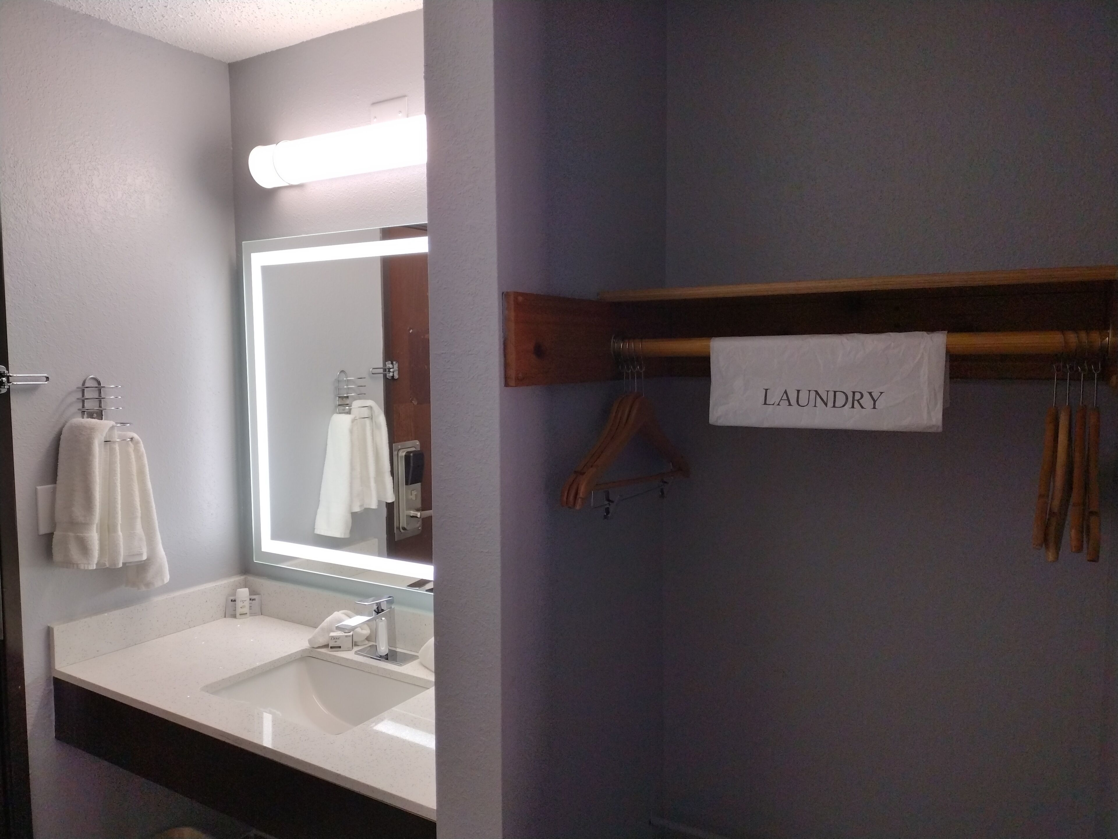 A bathroom with a white sink, a mirror, and a towel rack. There is a sign above the towel rack that reads "LAUNDRY".