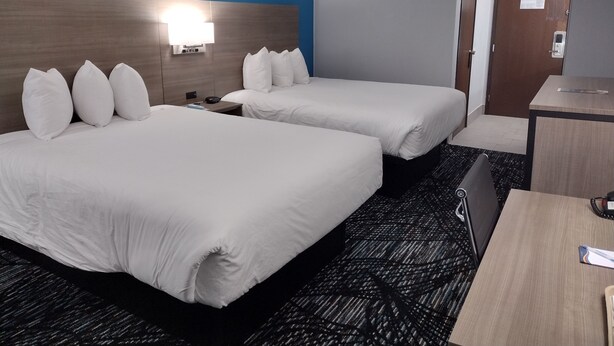 Ein Hotelzimmer mit zwei Betten, einem Schreibtisch und einem Nachttisch.