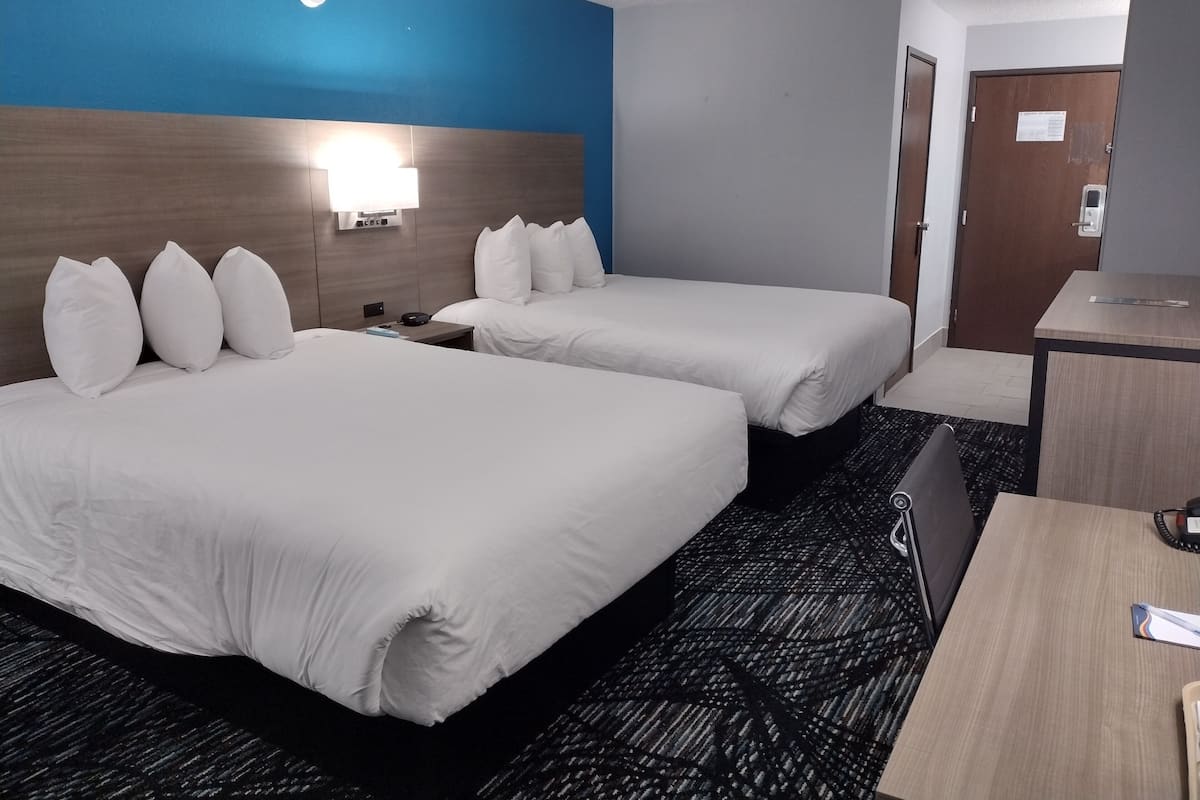 Ein Hotelzimmer mit zwei Betten, einem Schreibtisch und einem Nachttisch.