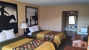 A hotel room with two beds, a desk, a mirror, and a kitchenette.