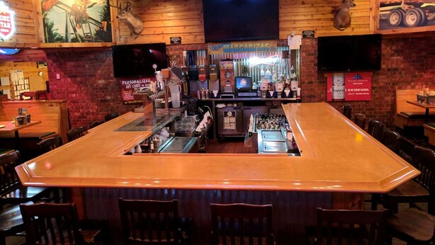 A bar area with a long counter, wooden walls, and various seating arrangements.