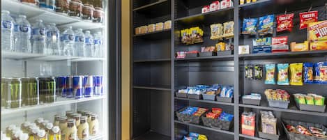 Ein Getränkekühler, gefüllt mit verschiedenen Getränken, und ein Snackregal mit einer Auswahl an verpackten Waren.