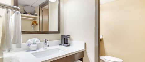 Une salle de bain avec un lavabo blanc, un miroir, des toilettes et un porte-serviettes.