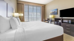 A hotel room with a large bed, a desk with a chair, a flat-screen TV, a microwave, and a large window with curtains. - Best Western Corpus Christi (Corpus Christi)