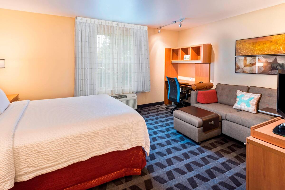 Een hotelkamer met een groot bed, een bank, een bureau en een televisie.