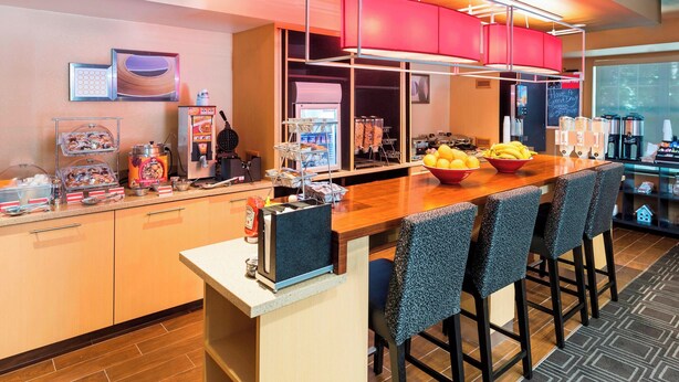 Una cocina moderna con barra, equipada con cafetera, frutero y diversos alimentos.