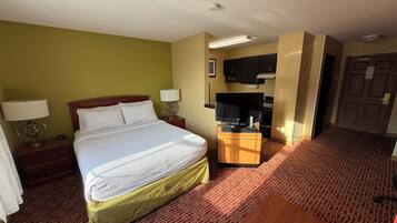 Une chambre d’hôtel avec un lit, un bureau avec une télévision, un four à micro-ondes et une porte.