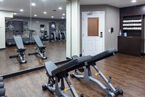 A gym with exercise equipment, a mirror, and a door. - TownePlace Suites by Marriott Dallas Plano/Legacy (Plano)