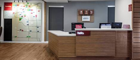 A hotel reception desk with a 'hello' sign, a map on the wall, and a sign indicating Marriott Bonvoy.