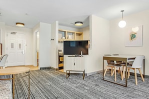 Een moderne hotelkamer met een eethoek, een flatscreen televisie en een kitchenette.