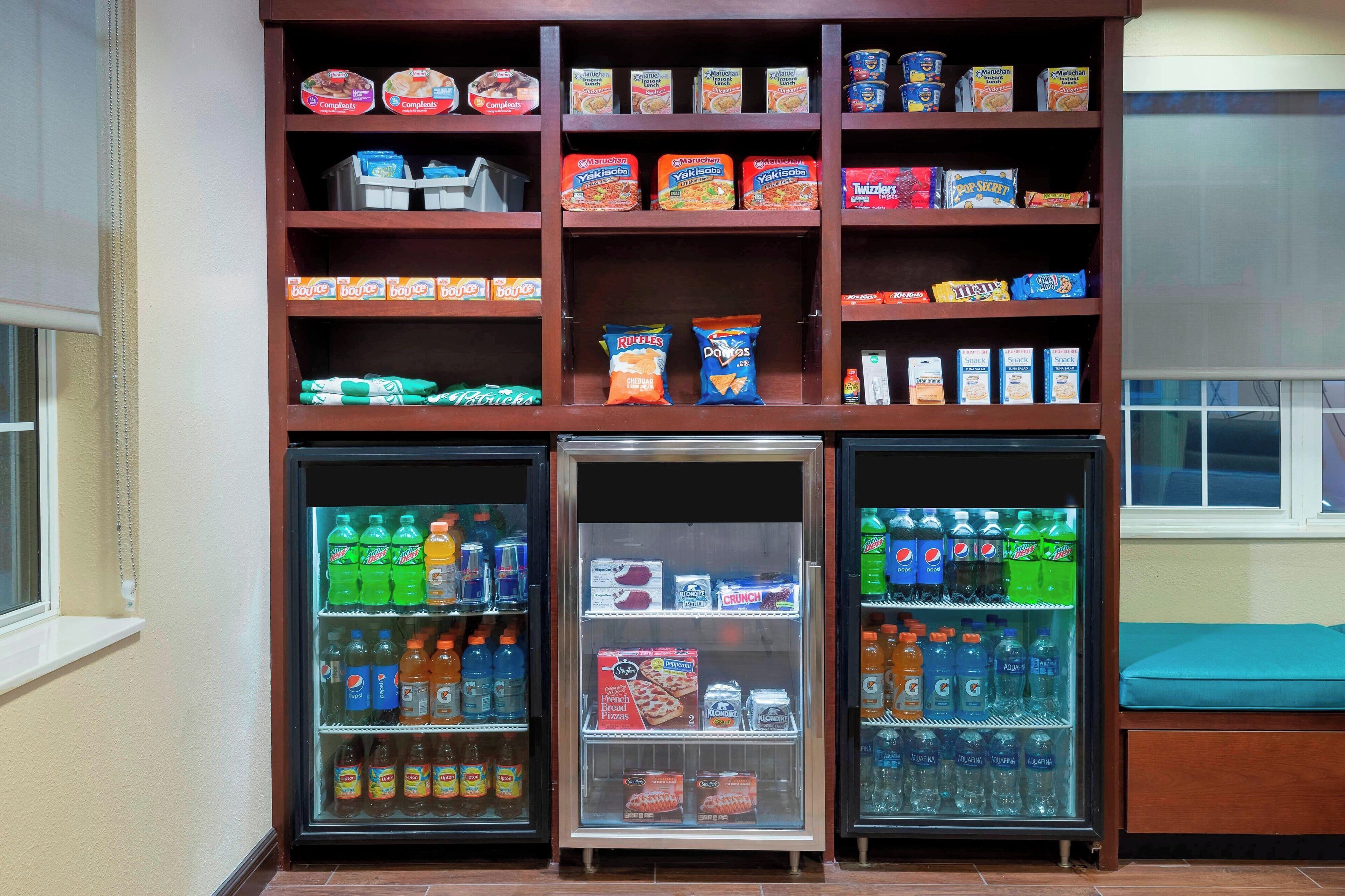 A vending machine with snacks and drinks, a refrigerator with beverages, and a window with a view.