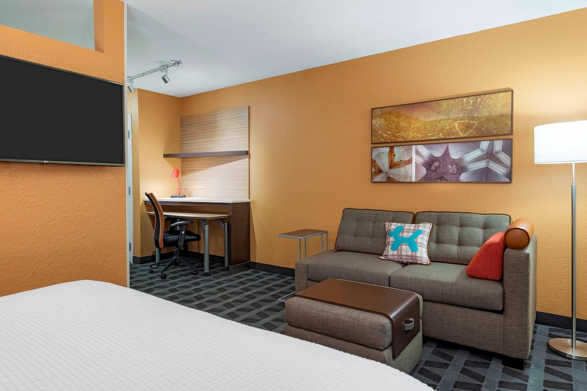 Een hotelkamer met een bed, een slaapbank, een bureau en een televisie.