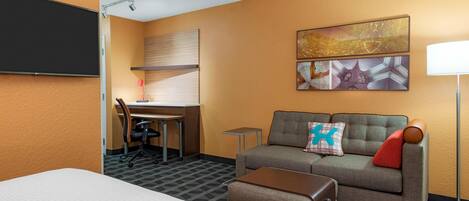 A hotel room with a bed, a sofa, a desk, and a TV.
