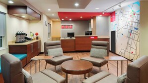 A modern hotel lobby with a reception desk, seating area, and a map on the wall. - TownePlace Suites by Marriott Savannah Midtown (Savannah)