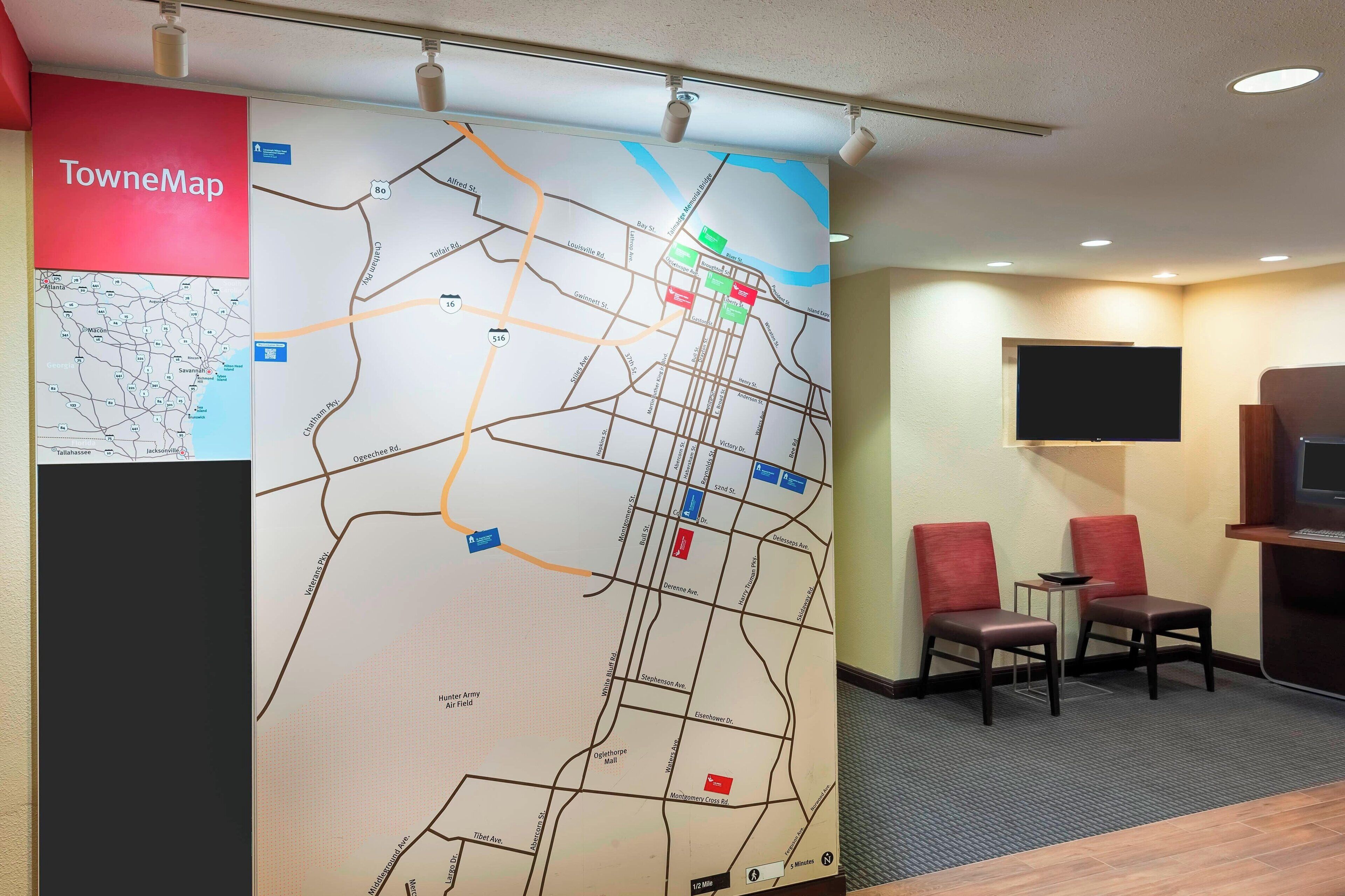 A map with marked locations, a television, and two red chairs in a room.