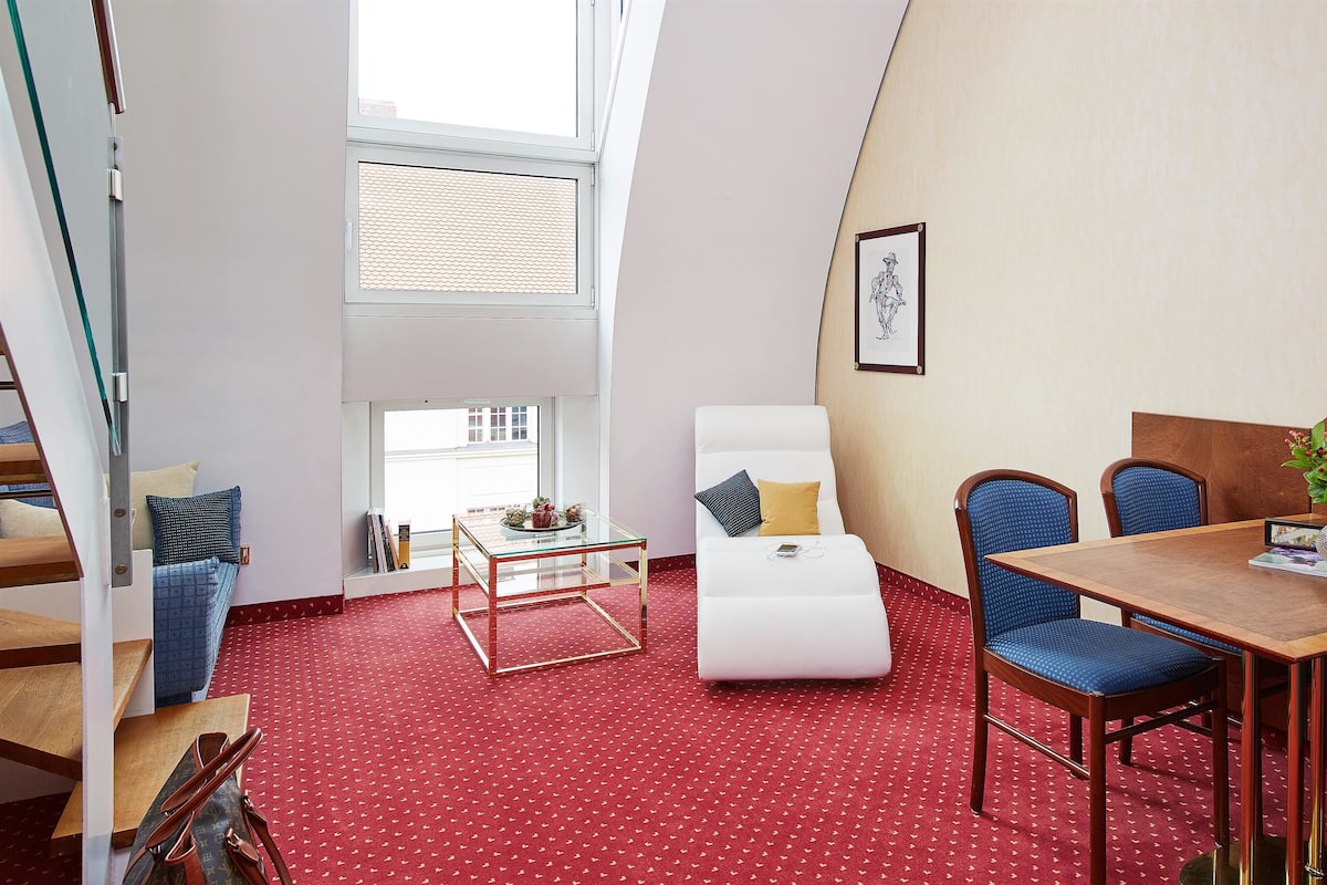 A modern room with a red carpet, a white sofa, a glass coffee table, and a dining table with chairs.